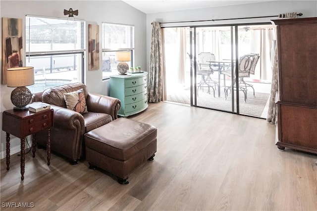 living area with lofted ceiling, ceiling fan, and light hardwood / wood-style floors