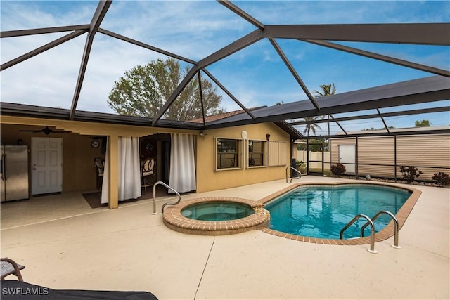 view of swimming pool featuring glass enclosure, a patio area, and an in ground hot tub