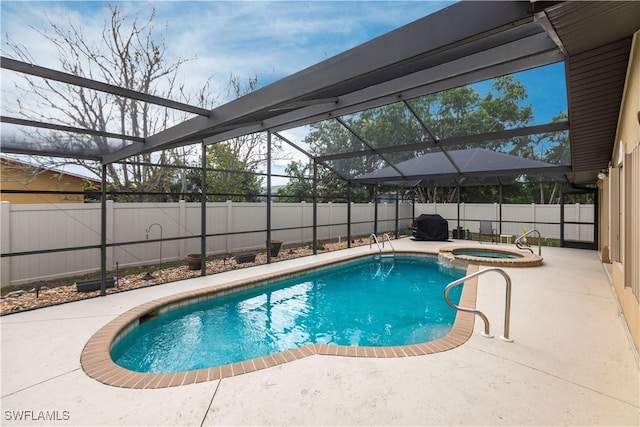 view of pool featuring an in ground hot tub, a patio area, and glass enclosure