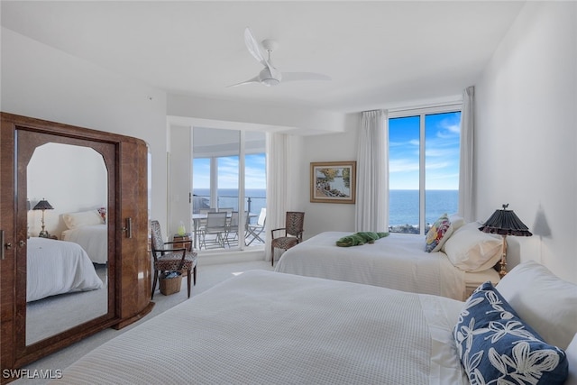 bedroom featuring access to exterior, carpet flooring, a water view, and a ceiling fan