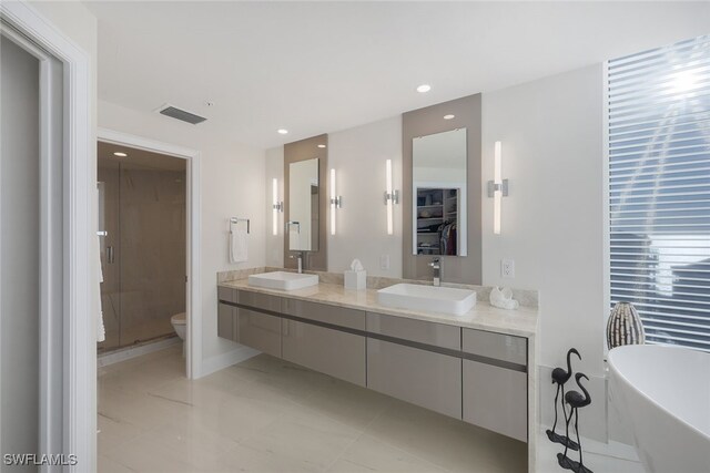 full bathroom featuring a stall shower, visible vents, a freestanding tub, and a sink