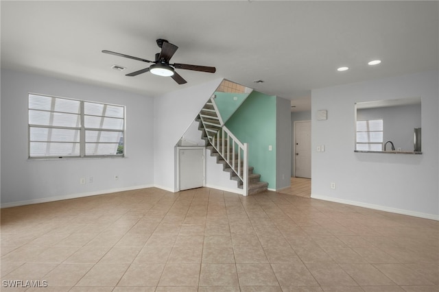 unfurnished living room with light tile patterned floors, a wealth of natural light, and ceiling fan