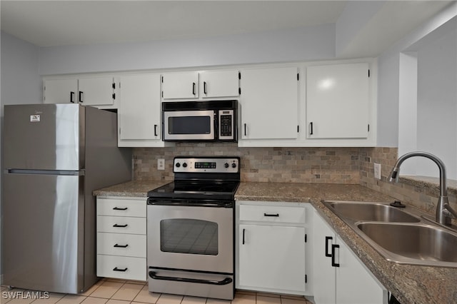 kitchen with sink, white cabinetry, light tile patterned floors, stainless steel appliances, and decorative backsplash