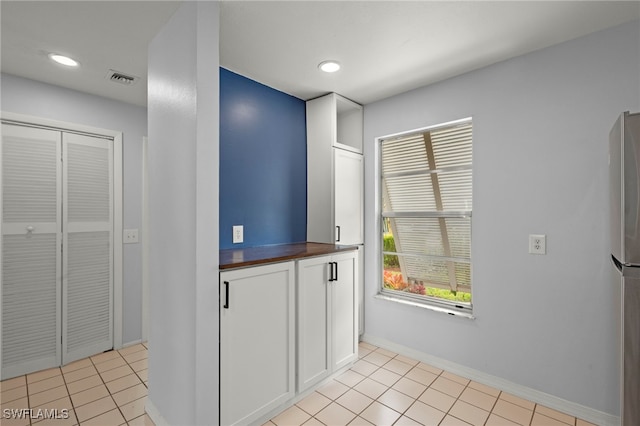 kitchen featuring light tile patterned floors, white cabinets, and butcher block countertops