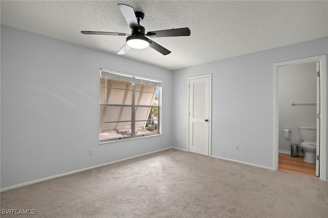 unfurnished bedroom featuring ensuite bath, ceiling fan, light carpet, a textured ceiling, and a closet