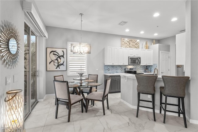 kitchen featuring pendant lighting, white cabinetry, stainless steel appliances, tasteful backsplash, and a kitchen breakfast bar