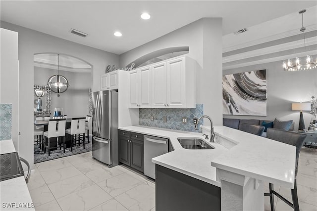 kitchen featuring white cabinetry, sink, stainless steel appliances, and pendant lighting