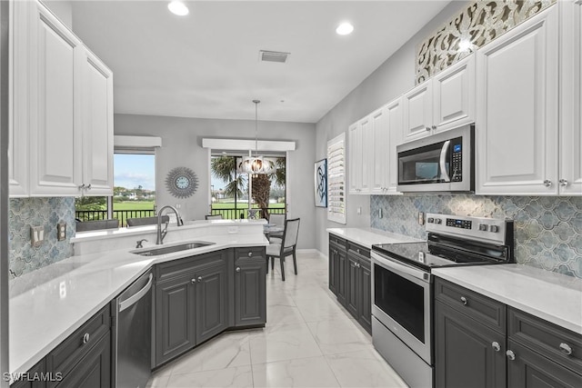 kitchen with white cabinets, appliances with stainless steel finishes, an inviting chandelier, sink, and hanging light fixtures