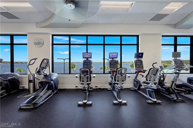 exercise room with a water view and a paneled ceiling