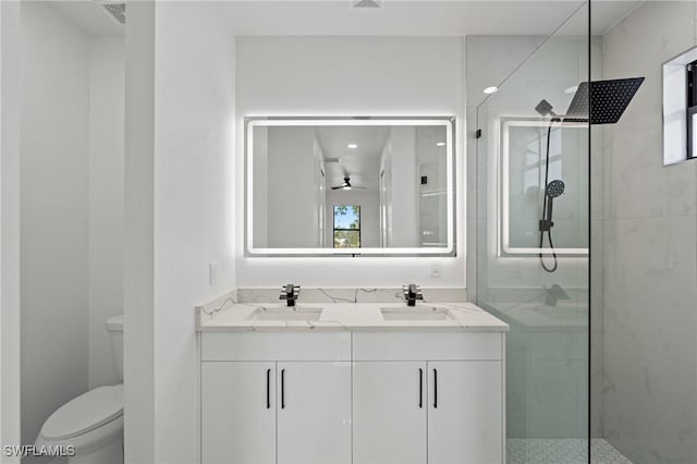 bathroom with vanity, tiled shower, and toilet