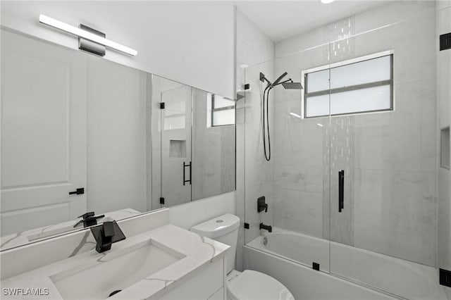 full bathroom featuring vanity, shower / bath combination with glass door, and toilet