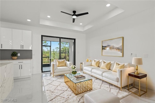 living room with light tile patterned floors, a tray ceiling, and ceiling fan