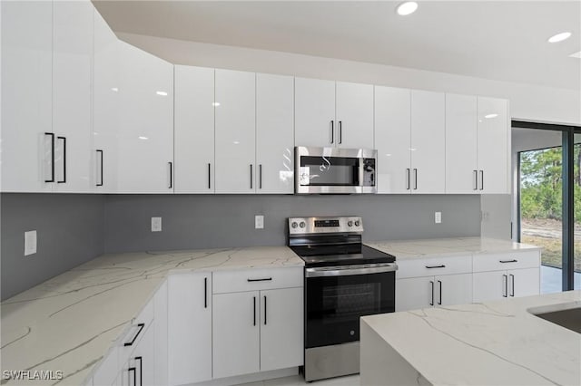 kitchen with light stone countertops, appliances with stainless steel finishes, and white cabinets