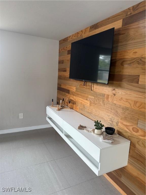 unfurnished living room featuring wood walls and tile patterned flooring