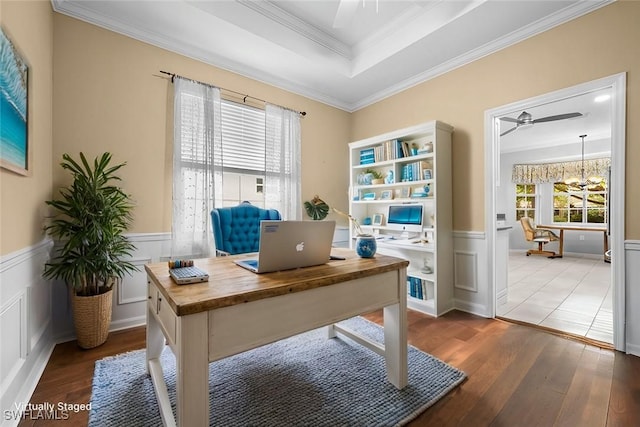 office area with a tray ceiling, dark hardwood / wood-style floors, ornamental molding, and ceiling fan with notable chandelier