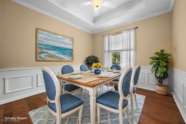 dining area with dark wood-type flooring, ornamental molding, a tray ceiling, and ceiling fan