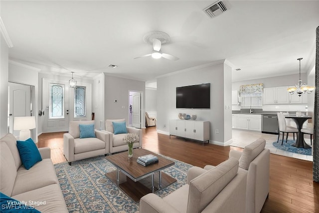 living room with ceiling fan with notable chandelier, sink, hardwood / wood-style floors, and crown molding