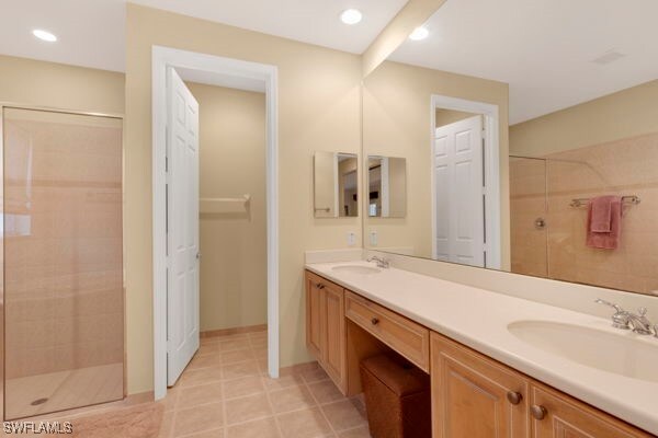 bathroom featuring a shower with door and vanity