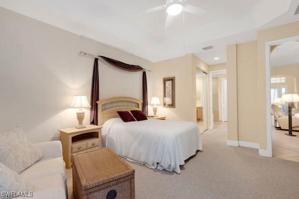 bedroom with ceiling fan, ensuite bathroom, and light colored carpet