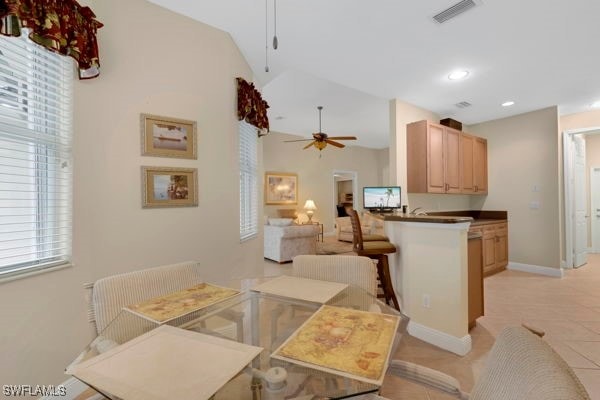 dining room featuring ceiling fan, vaulted ceiling, and light tile patterned floors