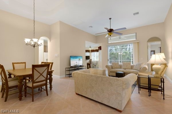 tiled living room featuring ceiling fan with notable chandelier