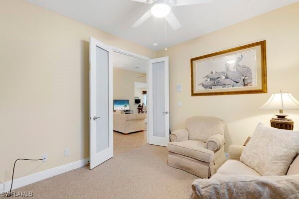 living area featuring french doors, ceiling fan, and light carpet