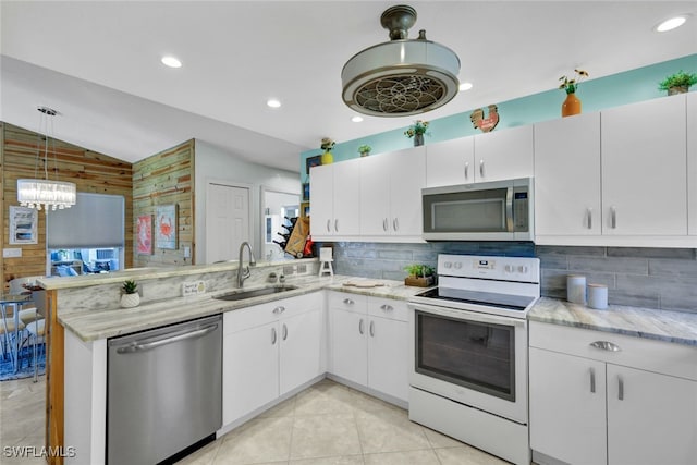 kitchen featuring lofted ceiling, sink, appliances with stainless steel finishes, kitchen peninsula, and white cabinets