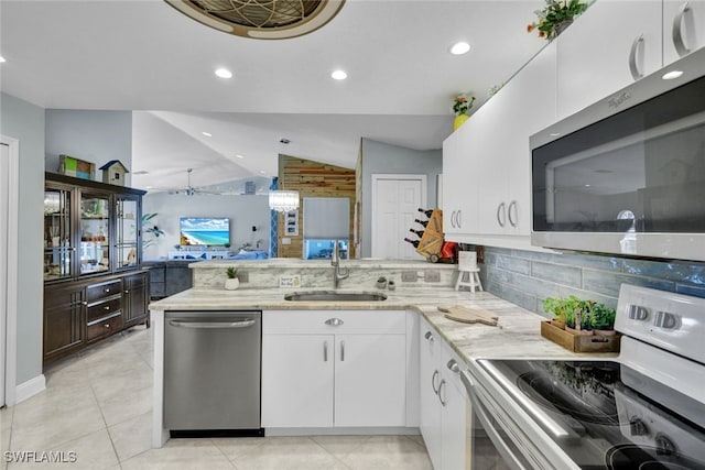 kitchen with sink, appliances with stainless steel finishes, white cabinetry, light stone counters, and kitchen peninsula