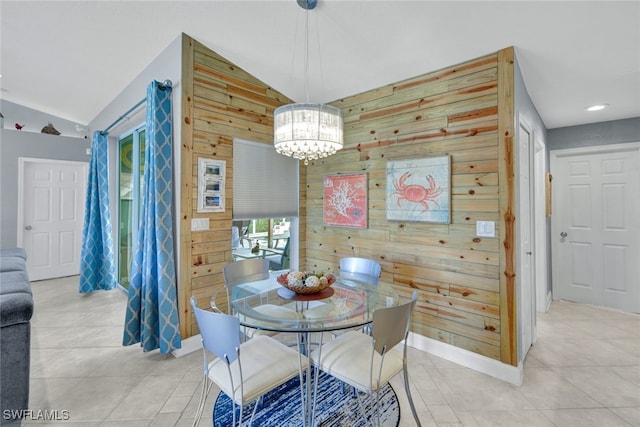 dining space with lofted ceiling, light tile patterned floors, an inviting chandelier, and wood walls