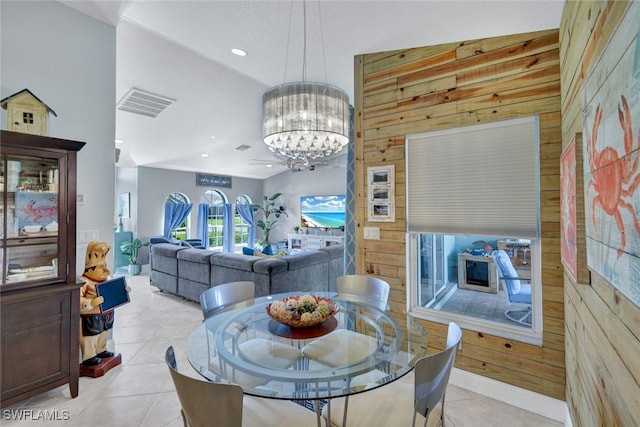 dining area featuring light tile patterned floors, a chandelier, and wood walls