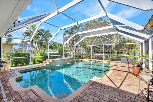 view of swimming pool with glass enclosure and a patio area