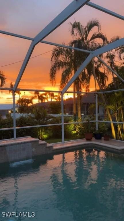 pool at dusk featuring a lanai