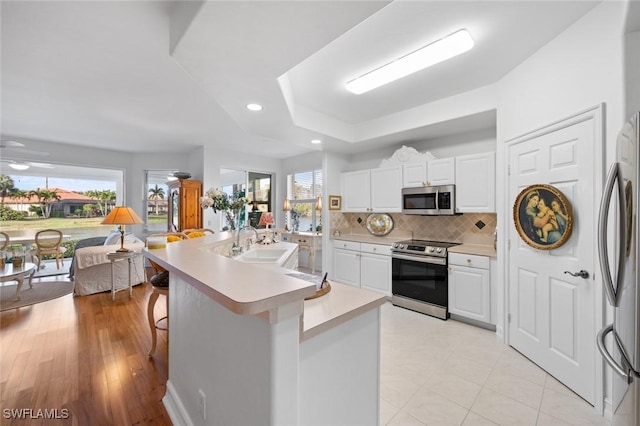 kitchen with sink, a breakfast bar, appliances with stainless steel finishes, white cabinetry, and an island with sink