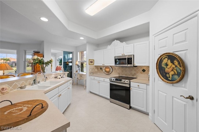 kitchen with sink, white cabinetry, tasteful backsplash, appliances with stainless steel finishes, and a raised ceiling