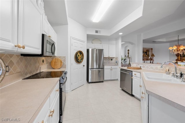 kitchen with sink, appliances with stainless steel finishes, white cabinets, decorative backsplash, and a raised ceiling