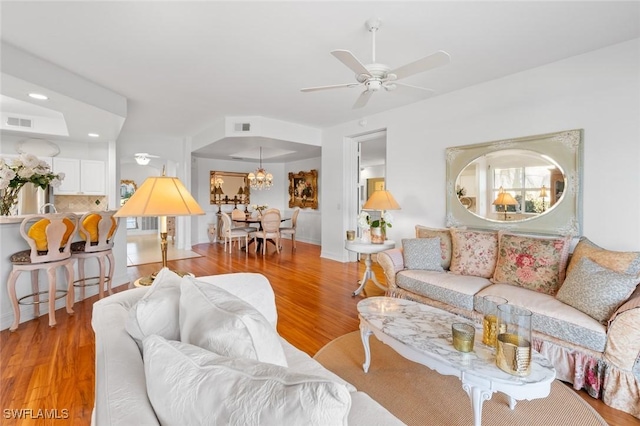 living room with ceiling fan with notable chandelier and light hardwood / wood-style floors