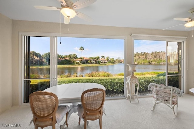 sunroom / solarium with a water view and ceiling fan