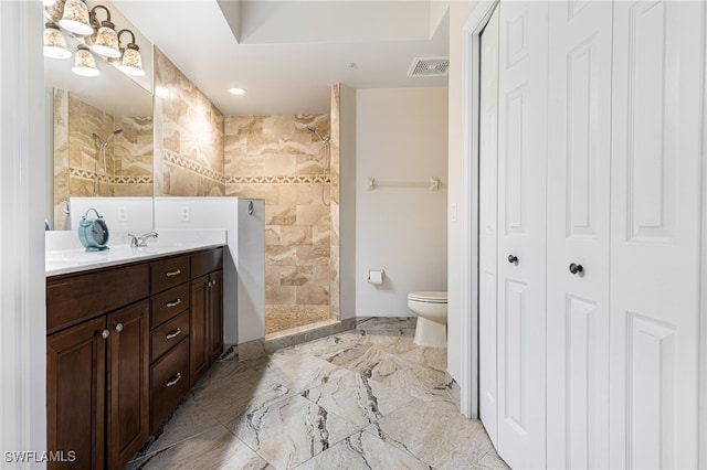 bathroom featuring toilet, vanity, and a tile shower