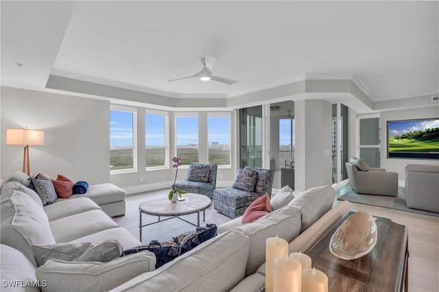living room featuring a ceiling fan, baseboards, ornamental molding, and light wood-style floors
