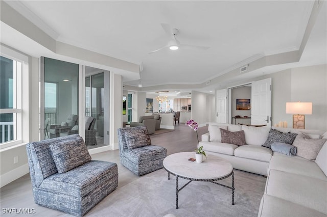 living room with a raised ceiling, ceiling fan, and crown molding