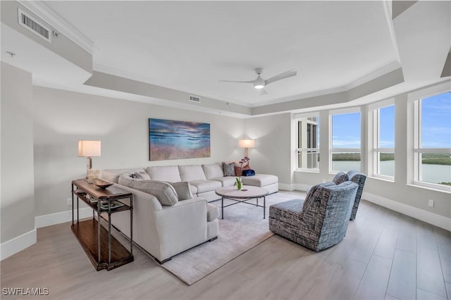 living area with visible vents, a raised ceiling, crown molding, and wood finished floors
