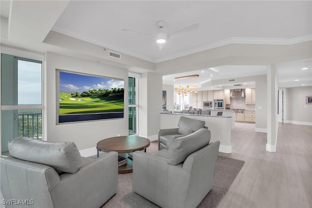 living area with crown molding, baseboards, a tray ceiling, and ceiling fan with notable chandelier
