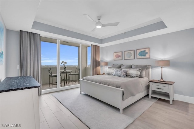bedroom featuring ceiling fan, access to exterior, light wood-type flooring, baseboards, and a tray ceiling