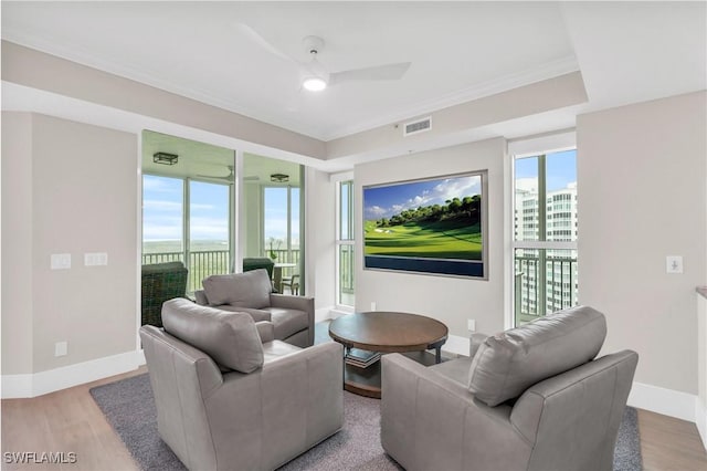 living room with hardwood / wood-style flooring, crown molding, and ceiling fan