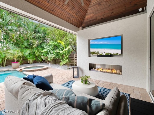 view of patio with an in ground hot tub and an outdoor living space with a fireplace