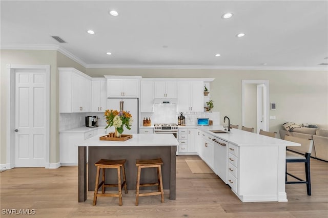 kitchen featuring kitchen peninsula, sink, white cabinets, white appliances, and a breakfast bar