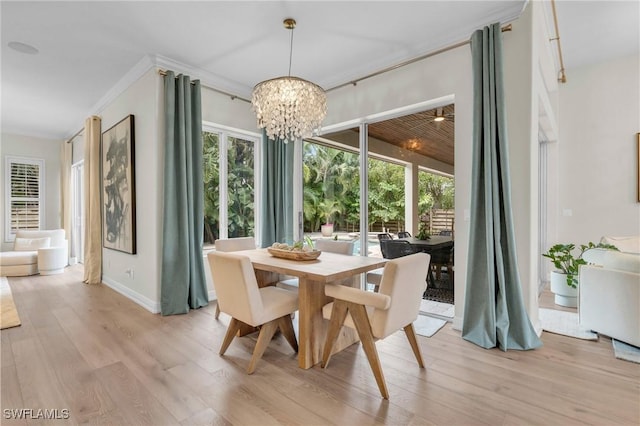 dining area with plenty of natural light, light hardwood / wood-style flooring, ornamental molding, and a notable chandelier