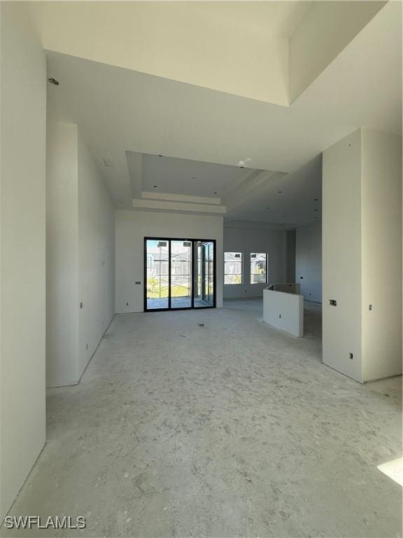 unfurnished living room featuring a tray ceiling and a healthy amount of sunlight