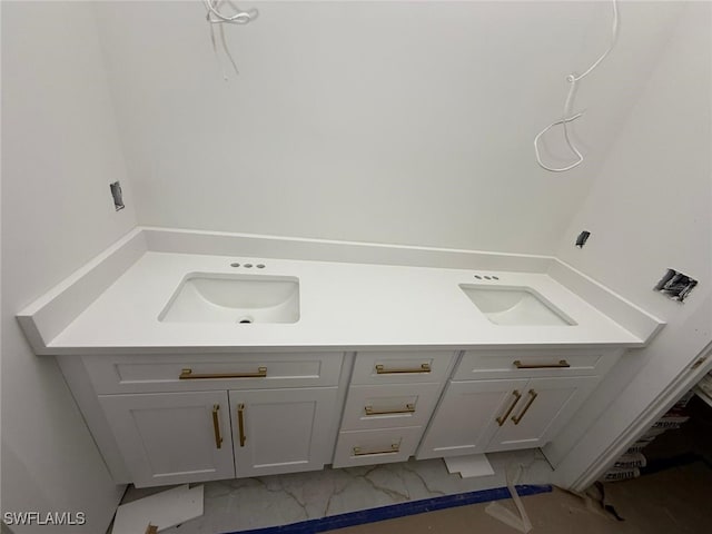 bathroom featuring double vanity, marble finish floor, and a sink