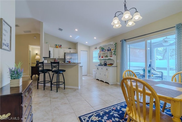 dining room featuring lofted ceiling, ceiling fan with notable chandelier, and light tile patterned floors